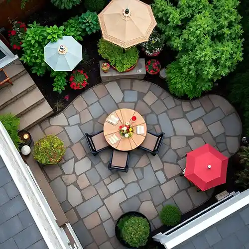 aerial view of patio made of stone with a table in the center and 3 umbrellas